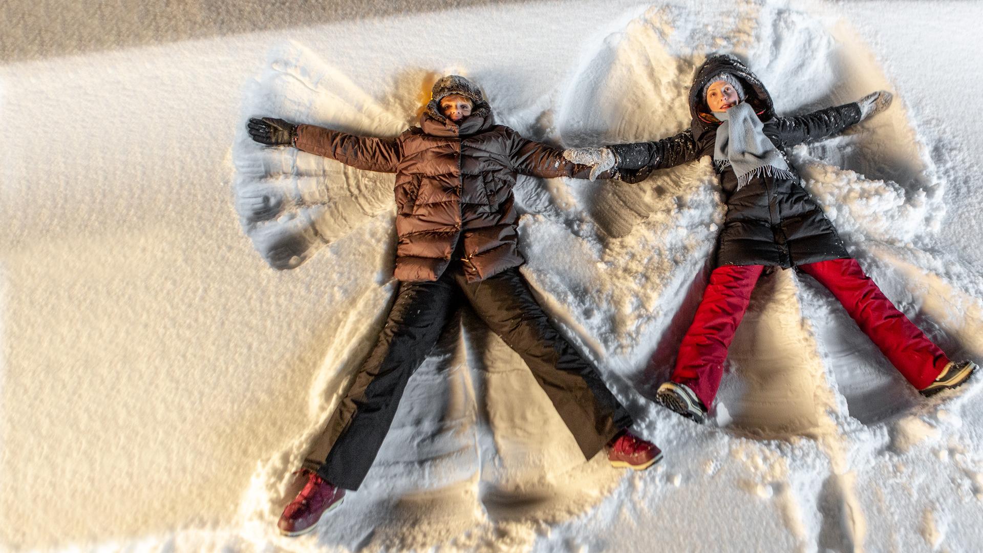 "Weihnachten im Schnee": Bastian (Anton Spieker), Annika (Katharina Schüttler) und Sanne (Inez Bjørg David) stehen nebeneinander und blicken in die Kamera. Bastian und Sanne tragen einen roten Strickpullover mit einem Rentier mit roter Nase. Im Hintergrund sind ein Tannenbaum und eine dunkle Holzhütte zu erkennen.