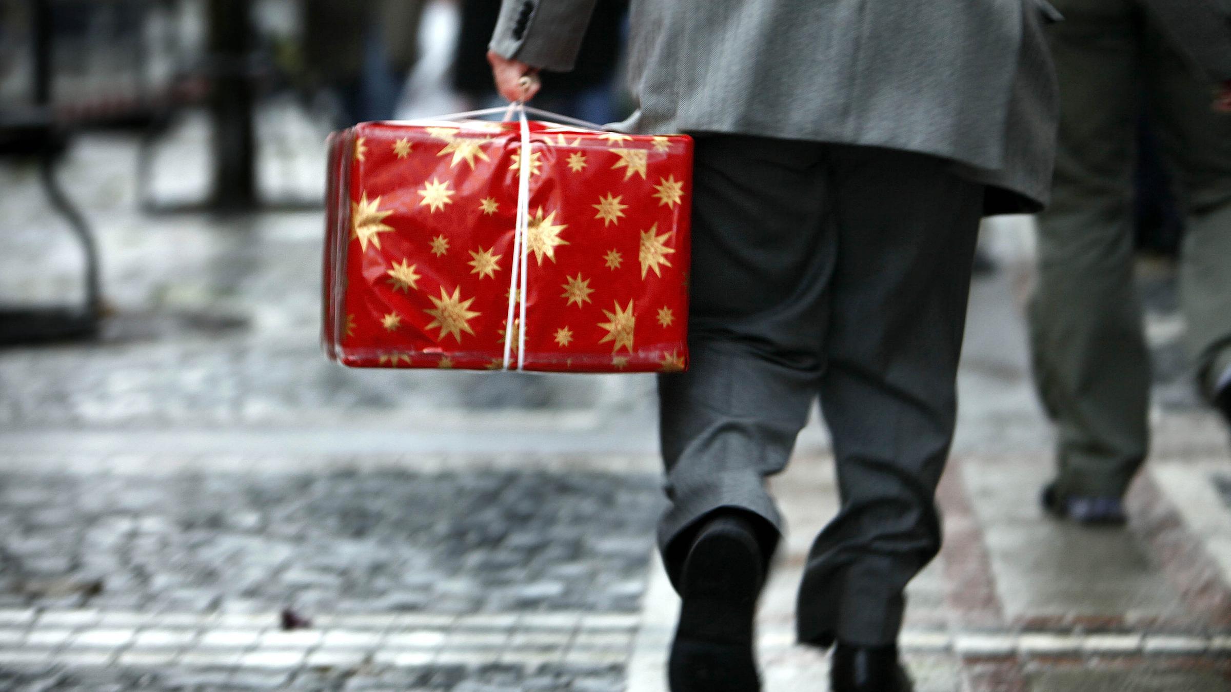 Archiv: Ein Mann trägt am 20.12.2008 ein in Geschenkpapier eingeschlagenes Paket