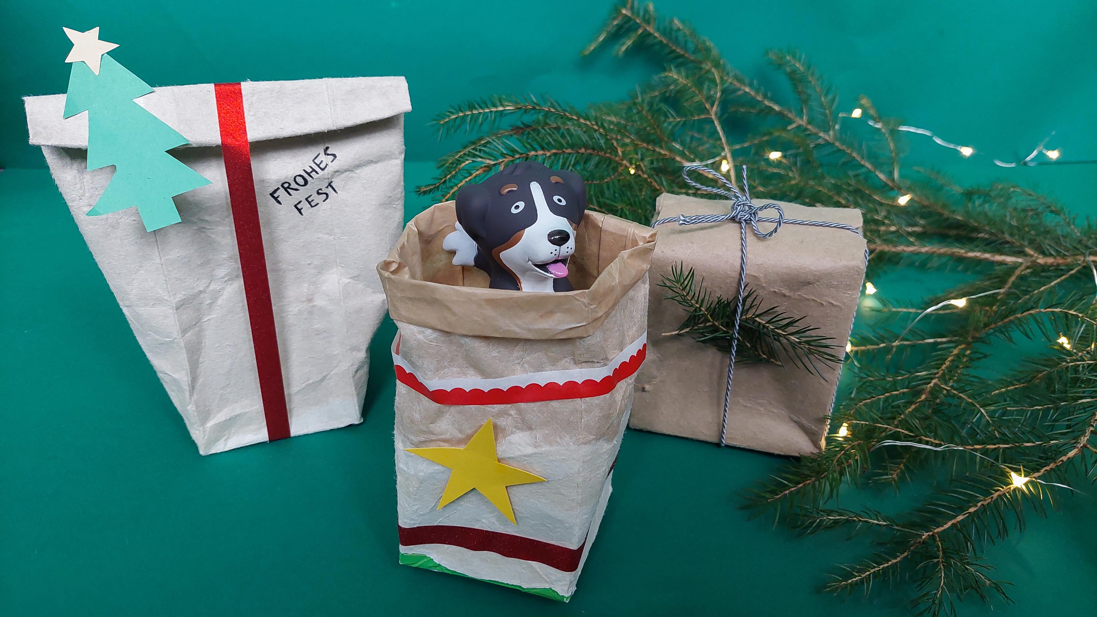 Drei verschiedene Verpackungen aus Milchkartons, weihnachtlich dekoriert mit rotem Band und Tannenzweigen.