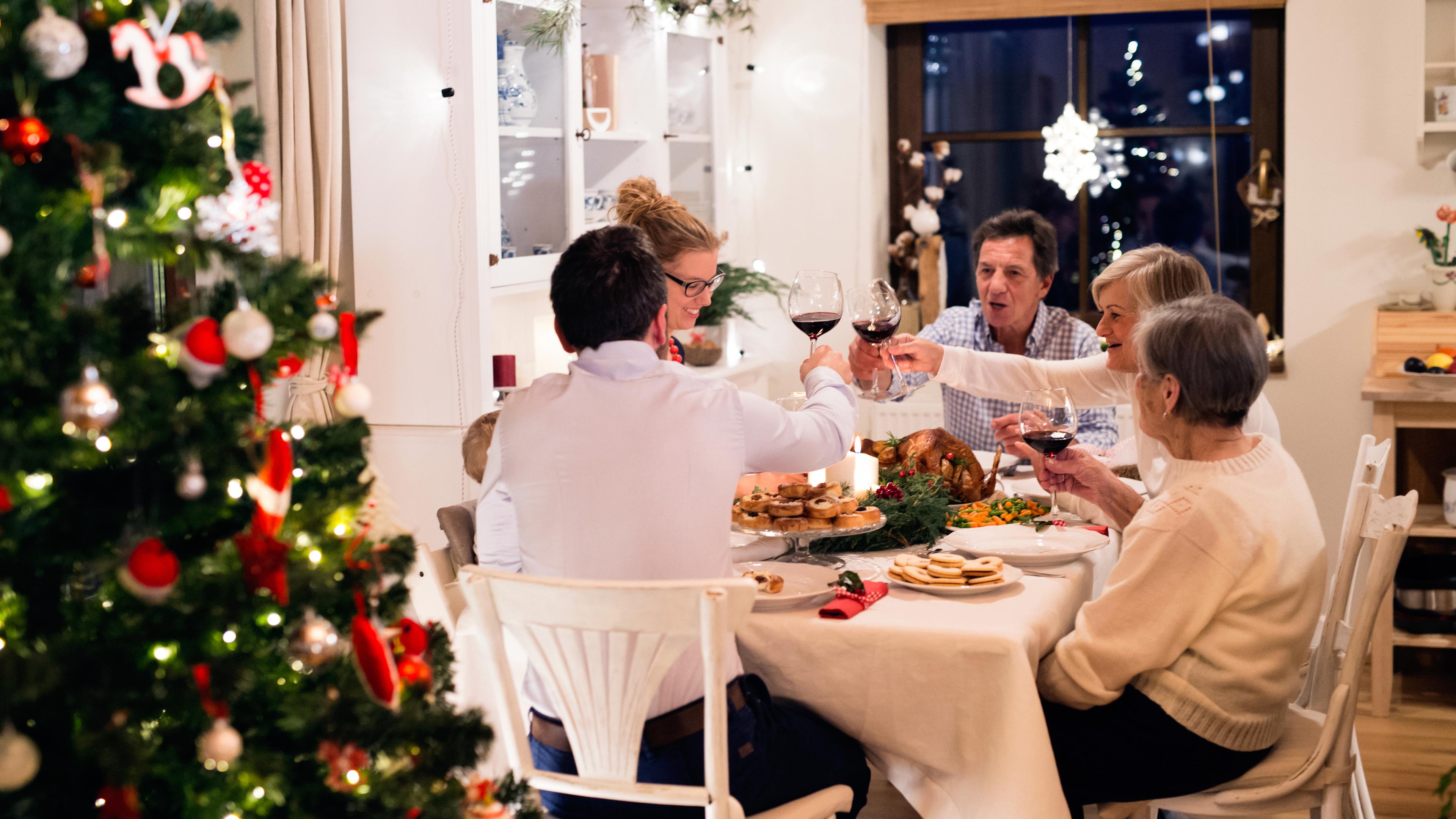 Eine Familie sitzt gemeinsam an einem Tisch und feiert Weihnachten.
