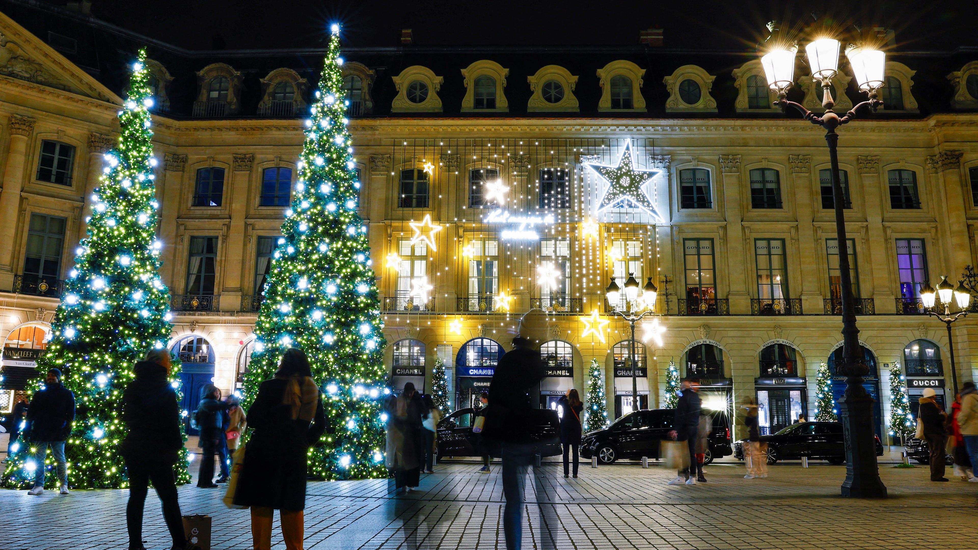 Menschen gehen um riesige Weihnachtsbäume auf dem Place Vendome herum, während die Weihnachtszeit in Paris, Frankreich, am 26.11.2023 beginnt.