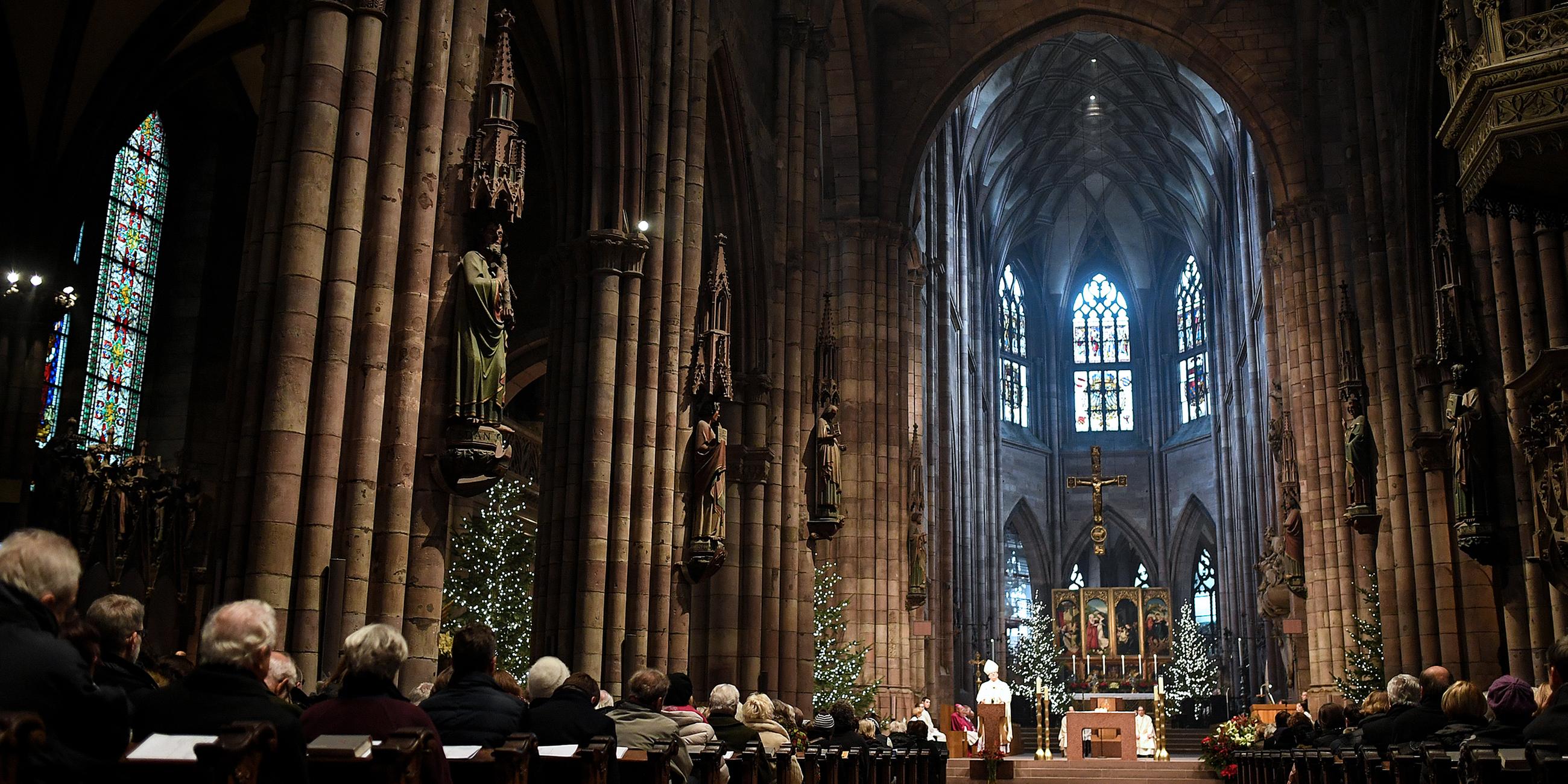 Kirchenbesucher hören im Münster beim Pontifikalamt zu Weihnachten der Predigt von Erzbischof Stephan Burger zu.