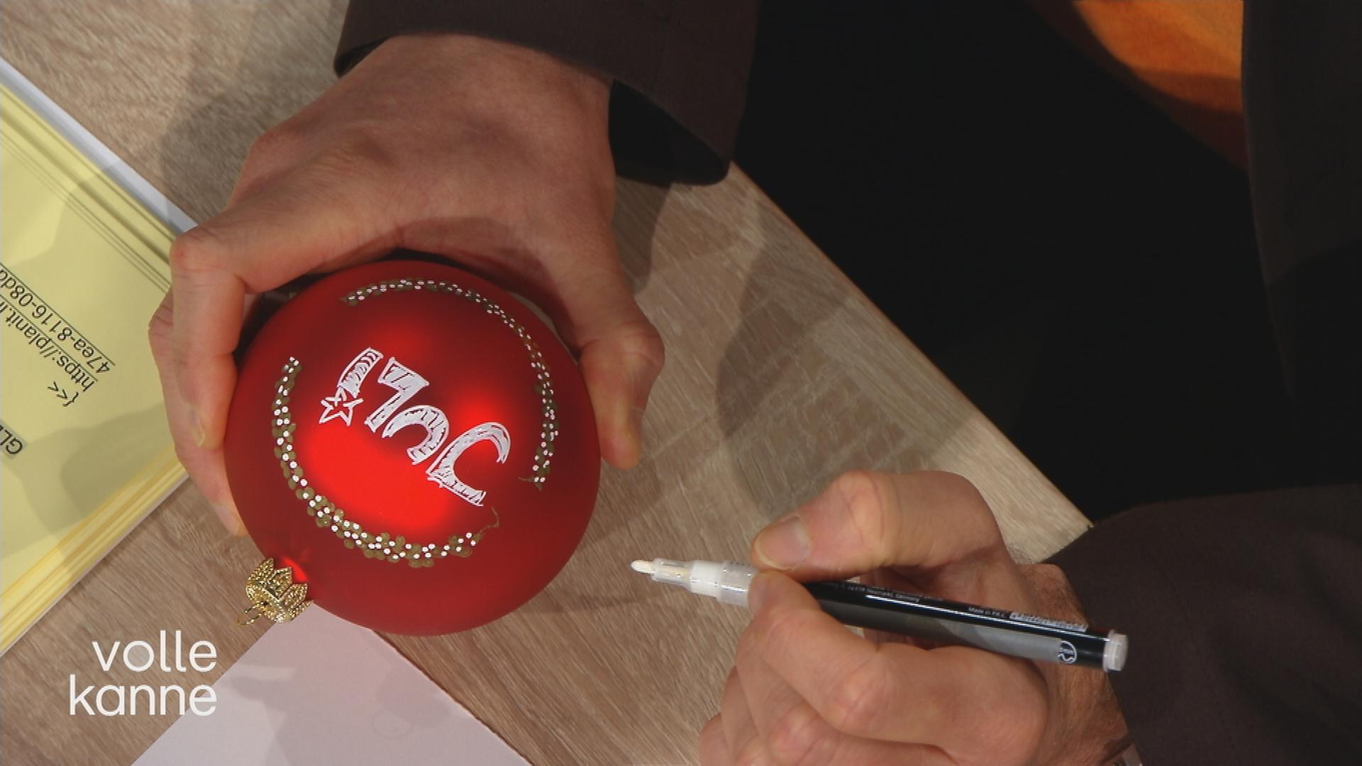 Florian Weiss malt auf eine Weihnachtskugel