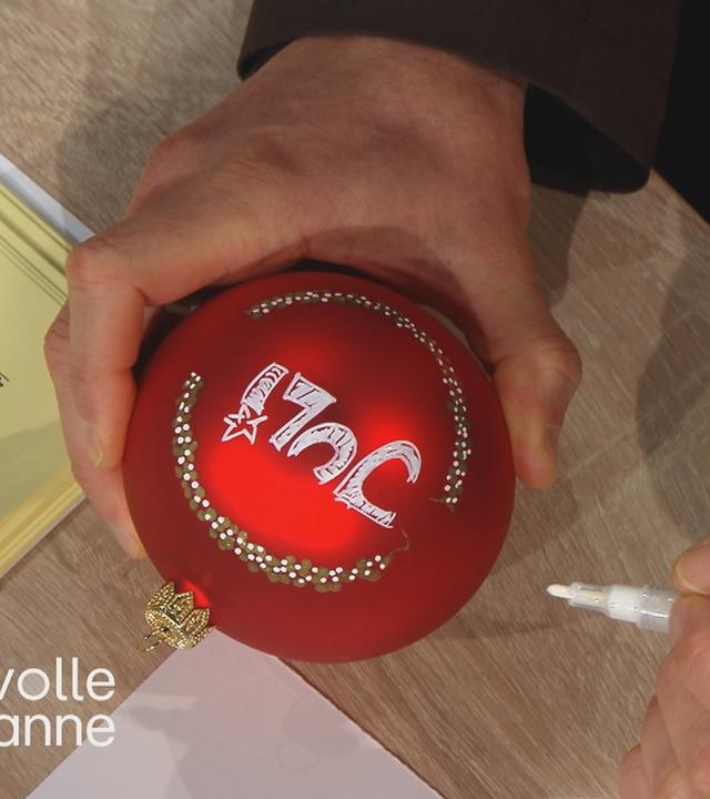 Florian Weiss malt auf eine Weihnachtskugel