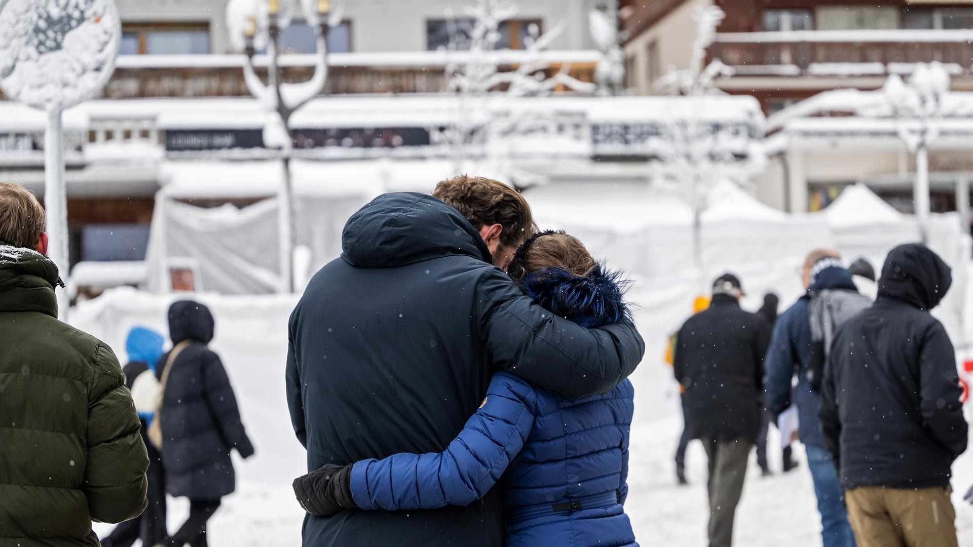 Trauernde Menschen stehen vor der mit Schnee und weissen Folien bedeckte Bar, wo das für viele tödliche Feuer ausgebrochen war