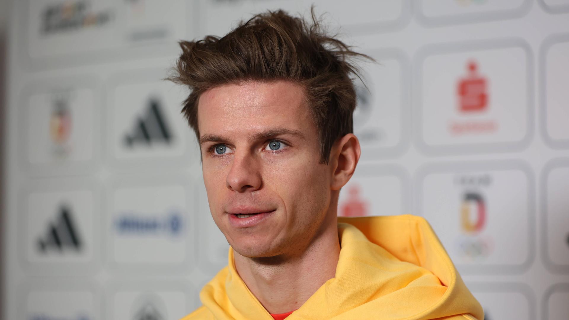Olympiasieger Andreas Wellinger steht in gelbem Pullover in der Mixed-Zone