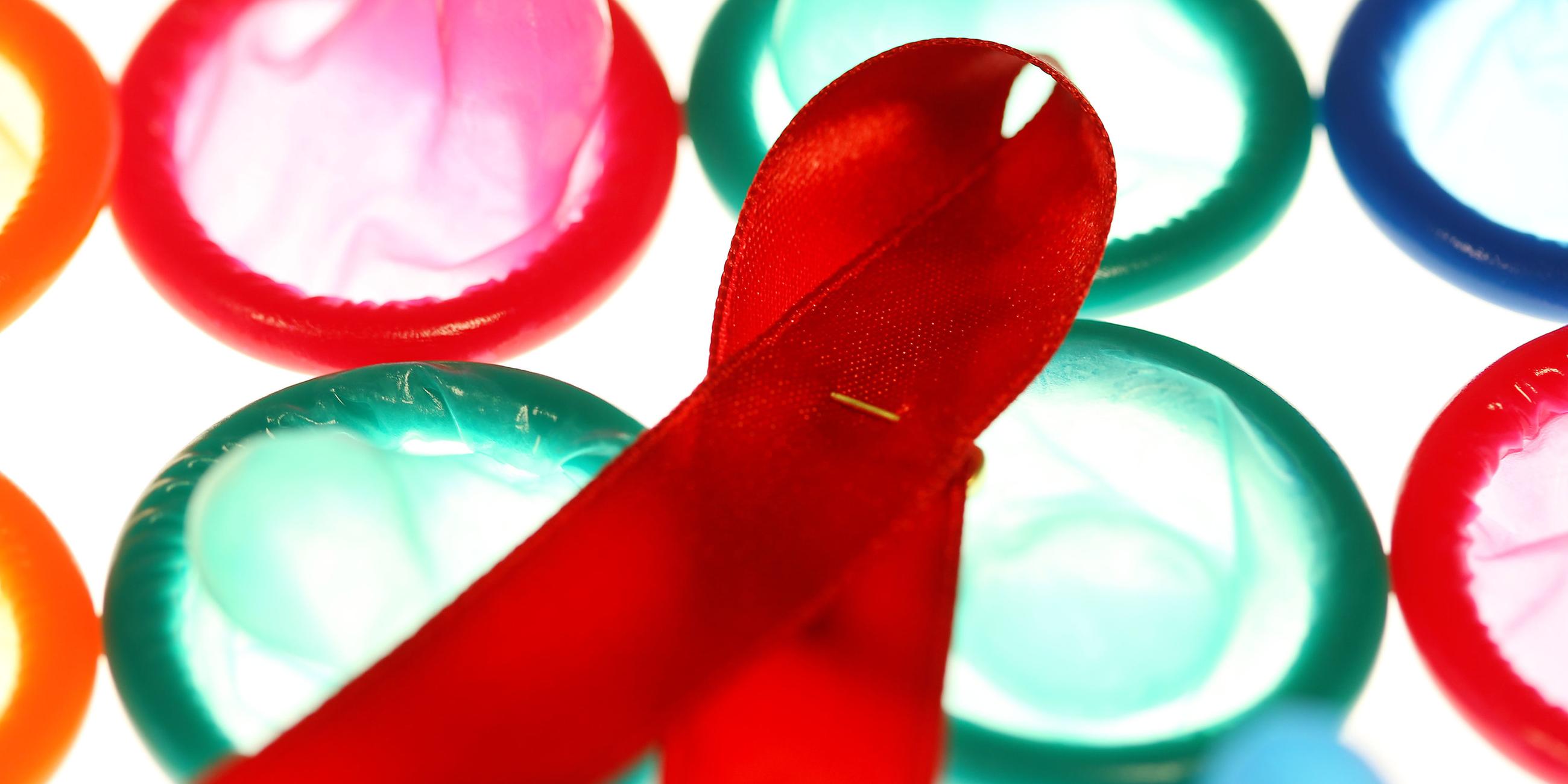 Eine Aidsschleife liegt am Montag (29.11.2010) in Köln auf einem Leuchttisch auf Kondomen.