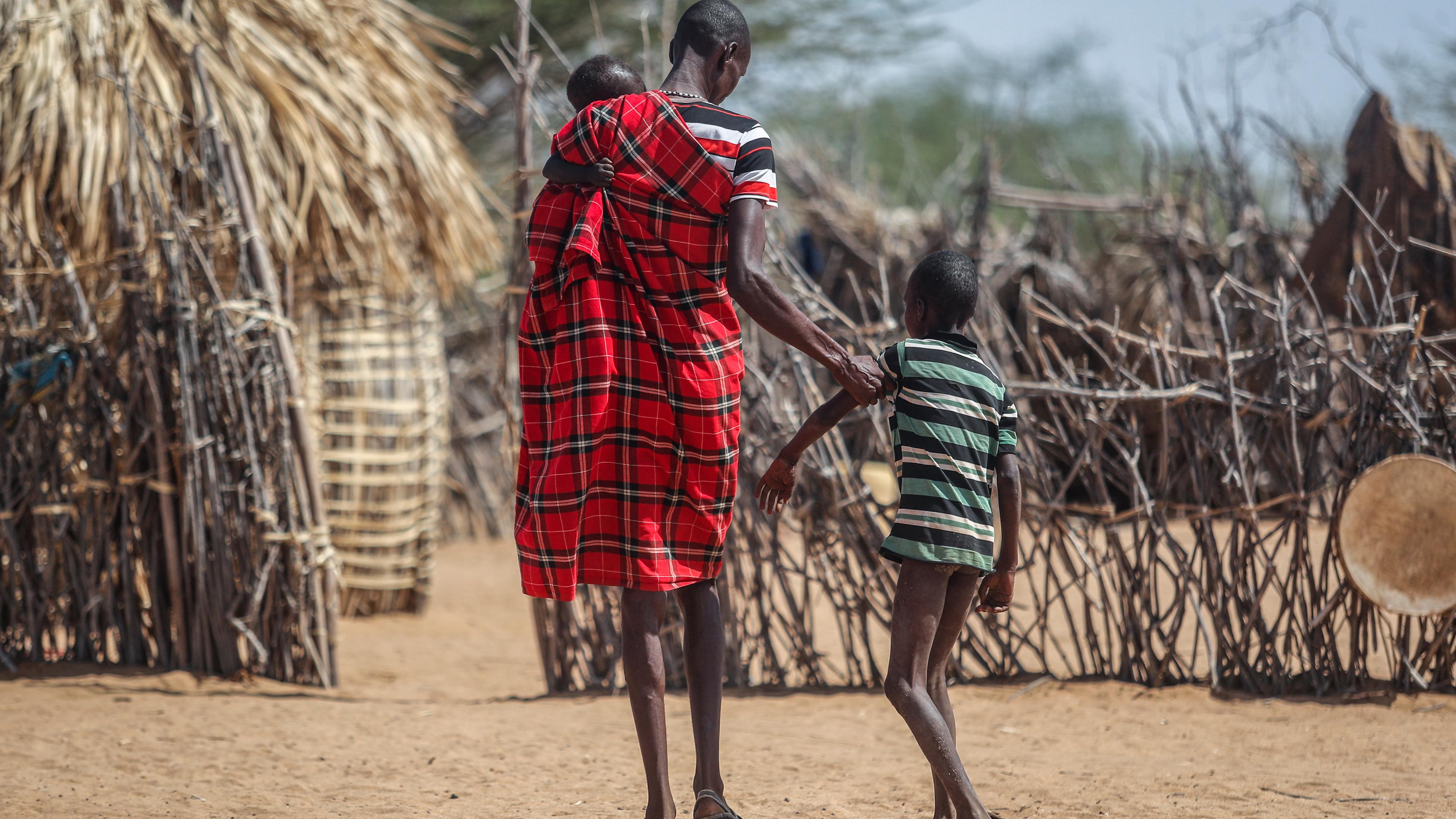 Ein Vater hilft seinem unterernährten Sohn beim Gehen in der Nähe ihrer Hütte in dem Dorf Lomoputh im Norden Kenias
