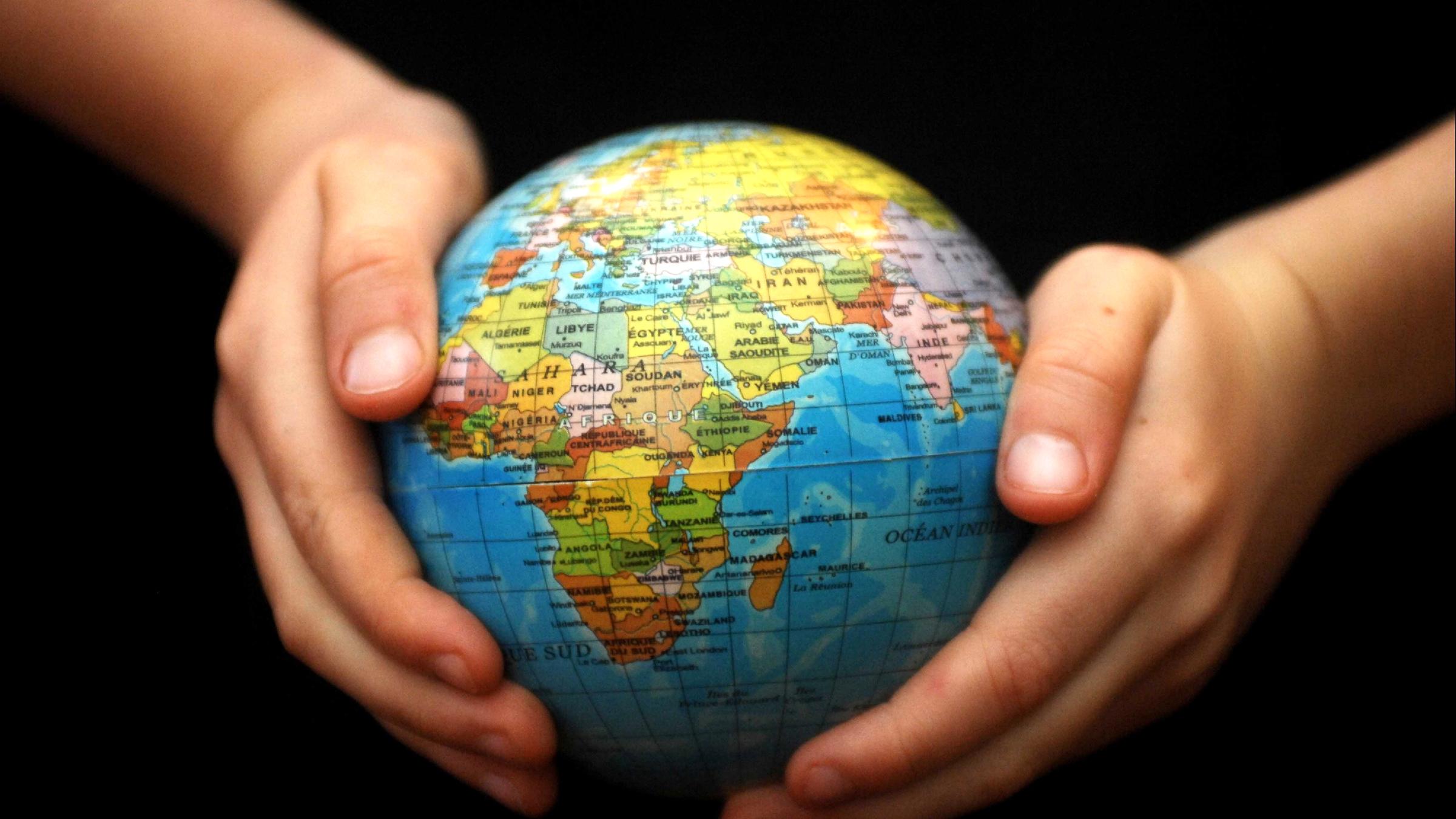 Hände halten einen Globus.