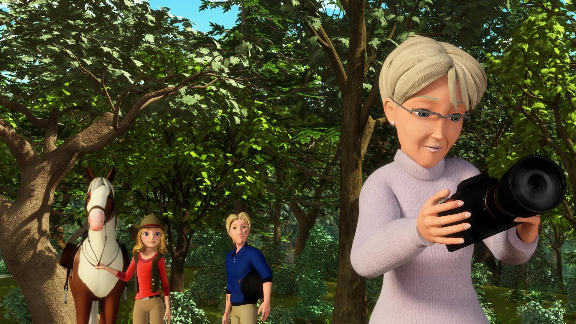 Hetty untersucht die Kamera. Wendy und Christian stehen mit ihren Pferden an der Leine im Hintergrund.