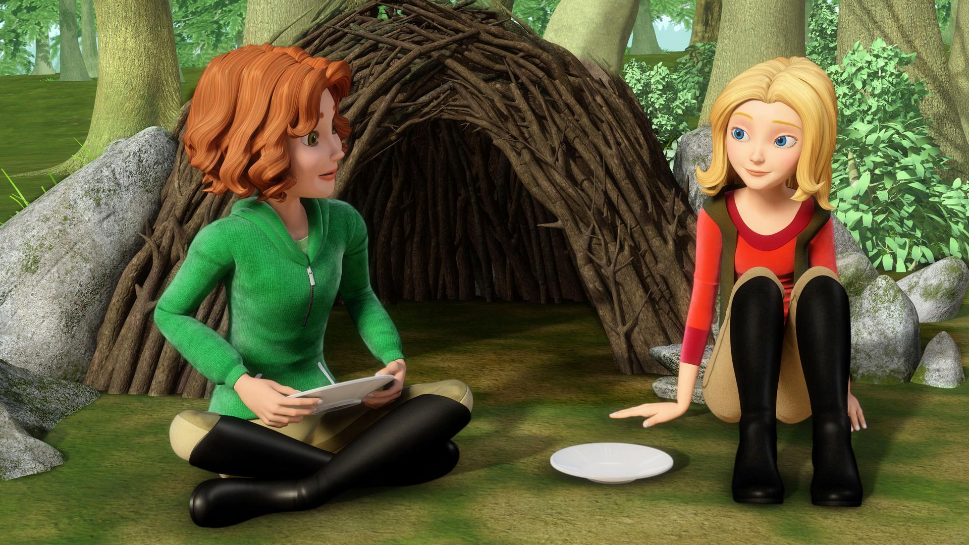 Wendy und Bianca sitzen auf dem Waldboden vor einer "Hütte" aus Ästen.