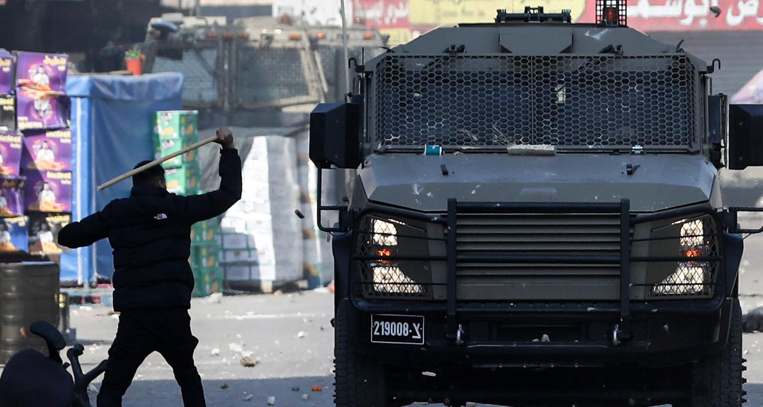 Ein Palästinenser steht vor einem Fahrzeug der israelischen Armee im Westjordanland