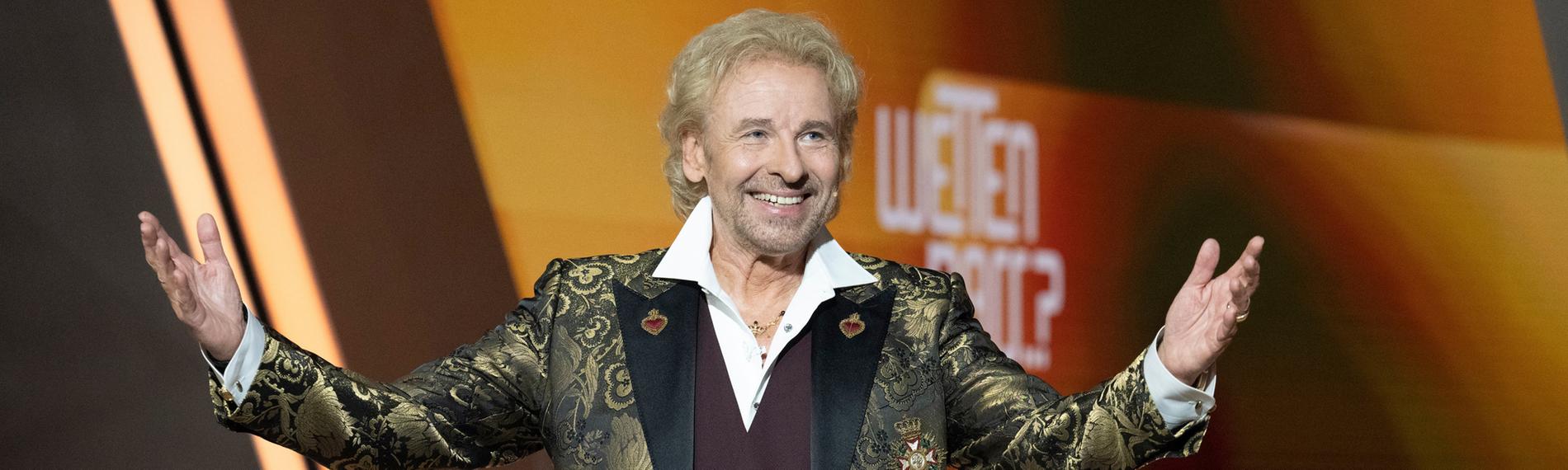 Thomas Gottschalk hebt beide Arme in die Luft und strahlt seitlich schauend ins Publikum. Im Hintergrund ist das "Wetten, dass..?"-Logo erkennbar.