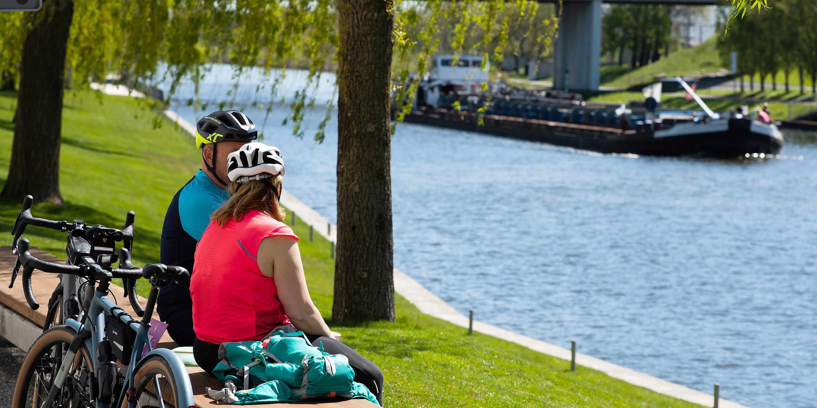 Zwei Radfahrer genießen das sommerliche Wetter bei einer Pause am Mittellandkanal.