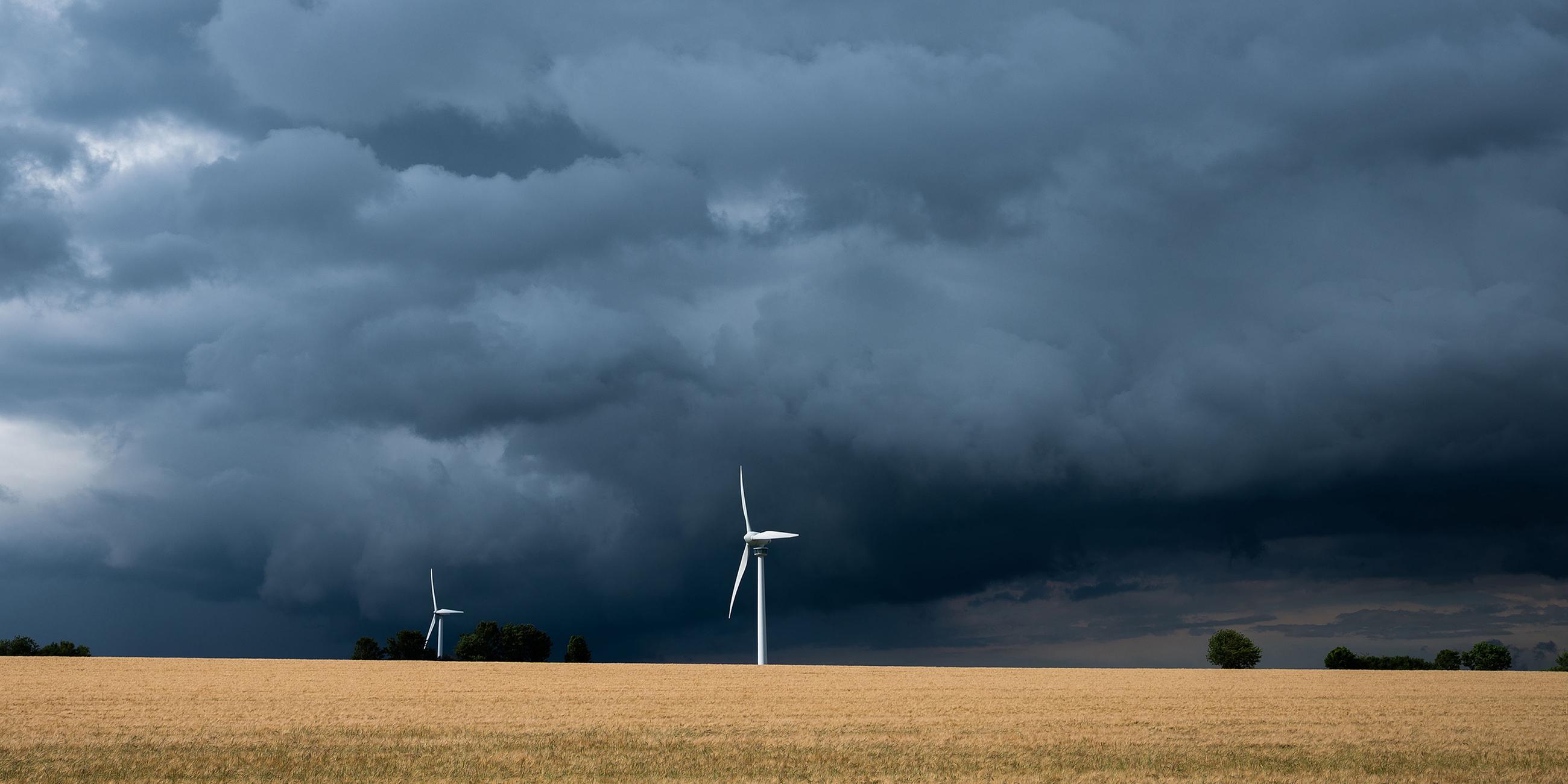 Niedersachsen, Hannover: Eine Gewitterzelle mit dunklen Wolken zieht über Windräder in der Region Hannover hinweg.