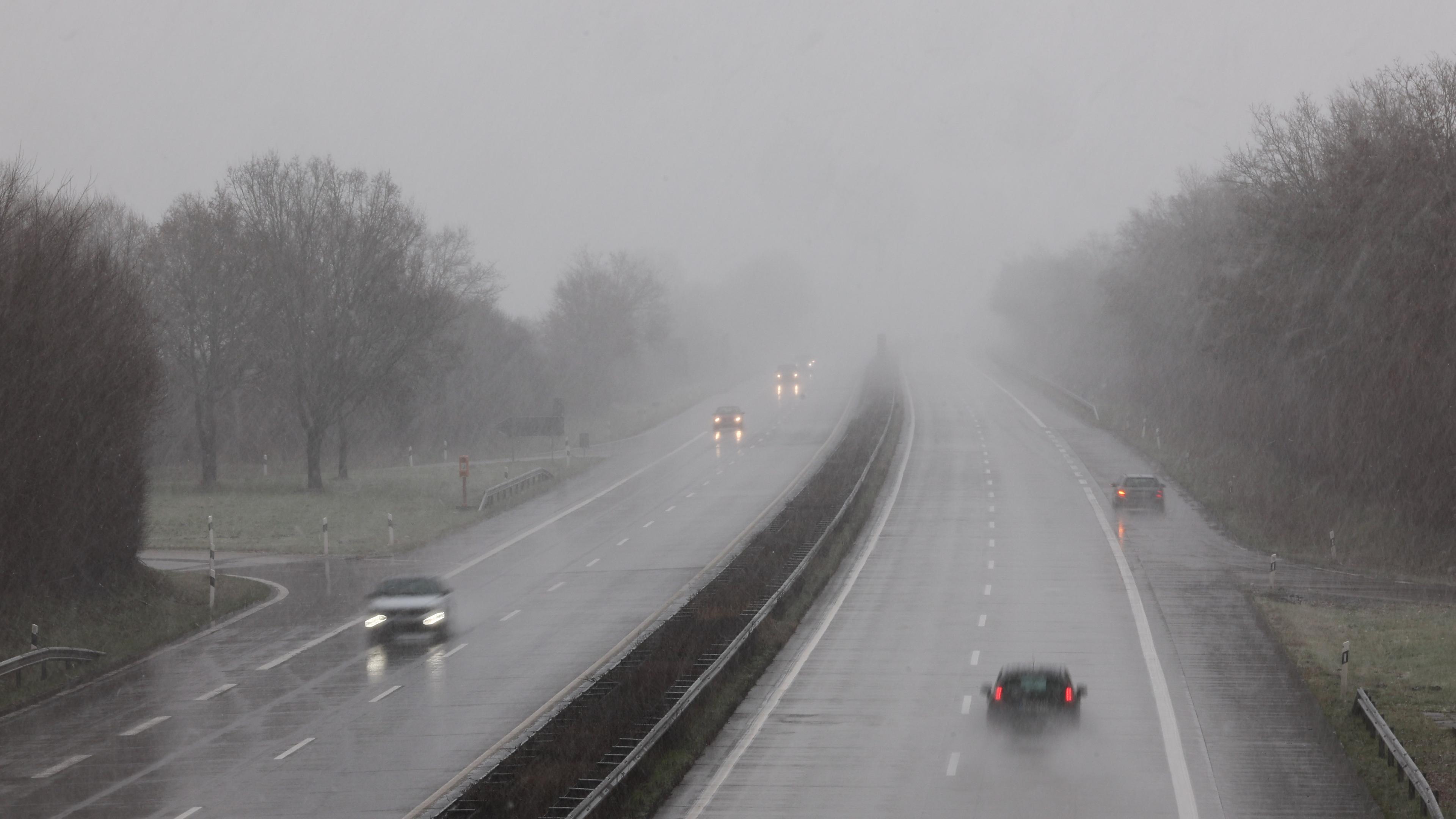 Autos fahren im Dämmerlicht durch den Regen auf einer Autobahn.
