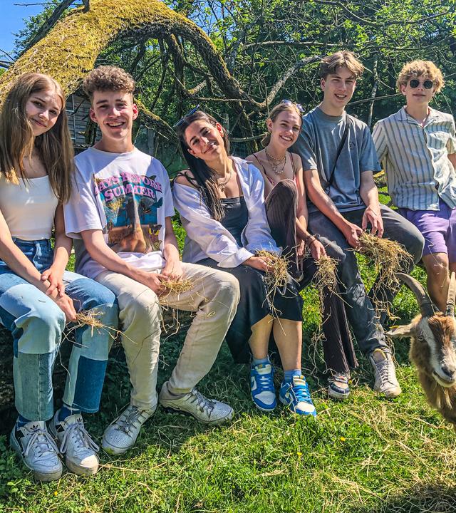 Toni, Jannis, Feli, Alexa, Rouven und Julius sitzen nebeneinander auf einem Baumstamm