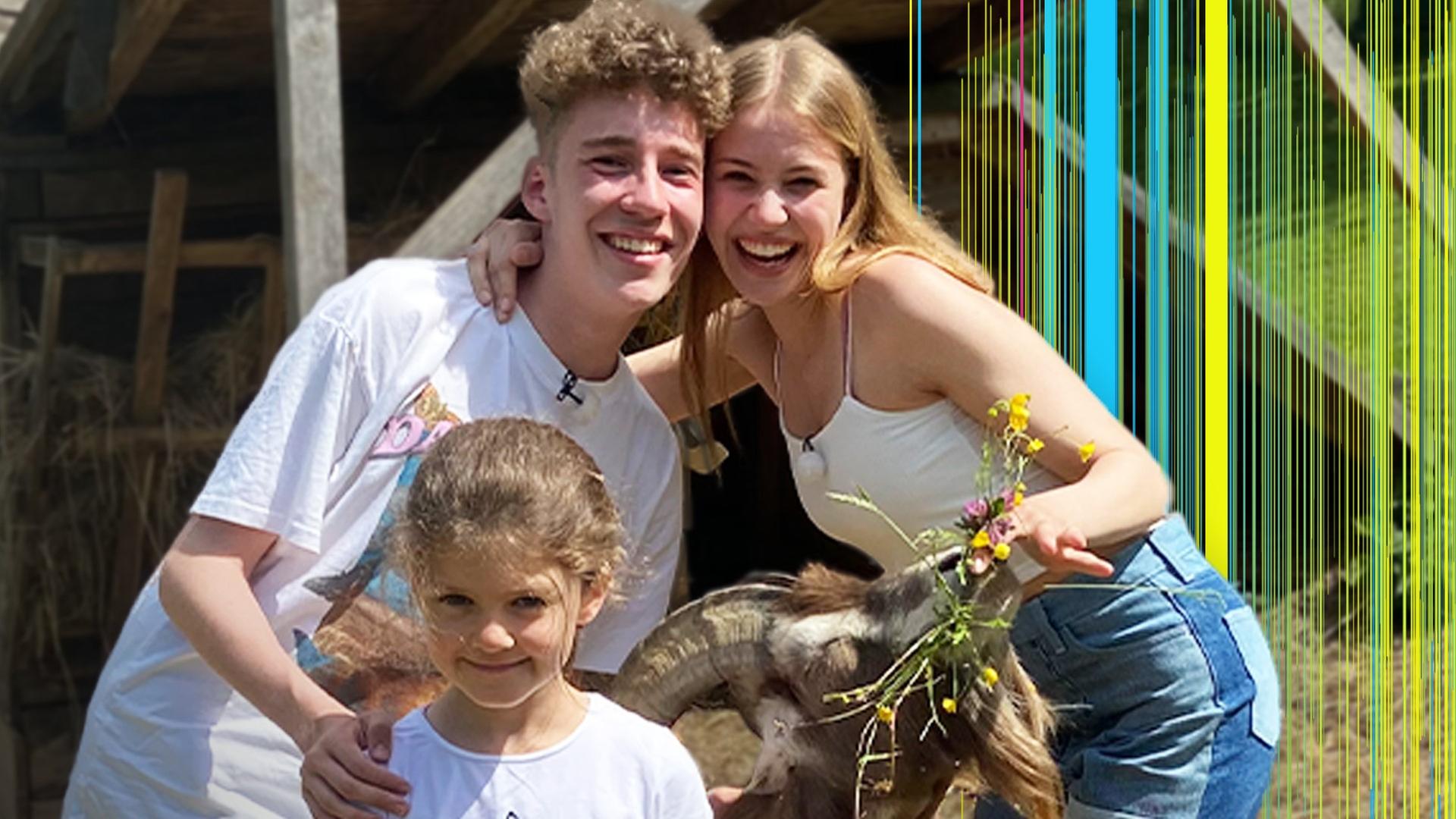 Jannis und Toni posieren mit einem Mädchen und einer Ziege für ein Selfie