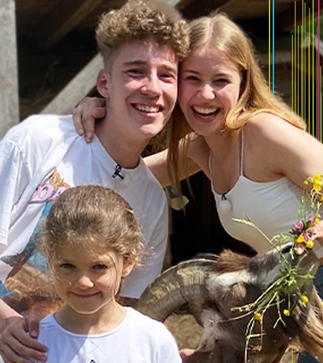 Jannis und Toni posieren mit einem Mädchen und einer Ziege für ein Selfie