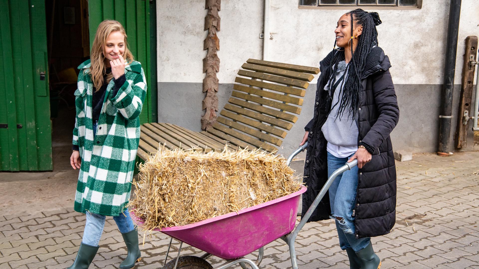 Janina und Feli schieben eine Schubkarre mit Stroh