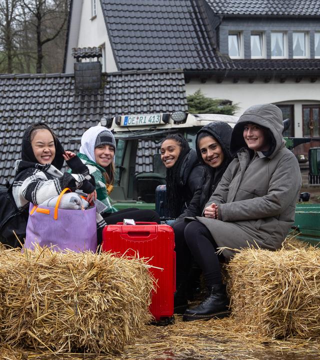 Alina, Feli, Hilla, Janina und My sitzen auf einem Traktoranhänger