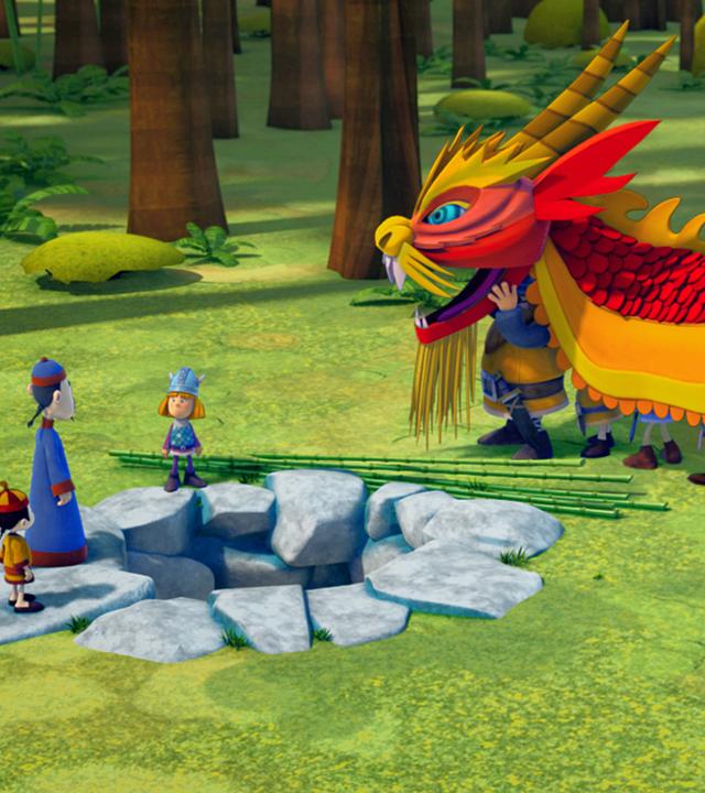 Die Wikinger haben sich als Drache verkleidet, um Ming und Qi zu helfen. Die beiden stehen links neben Wickie und sehen zum Drachenkostüm.