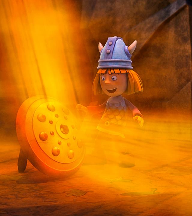 Wickie steht in der Höhle vor einem Schild, von dem ein enormer orange-goldener Lichterglanz ausgeht.