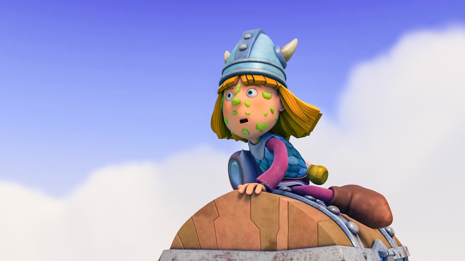 Wickie sitzt auf der Schatzkiste. Dabei hat er etwas Grünes im Gesicht kleben und schaut gespannt in die Ferne. 