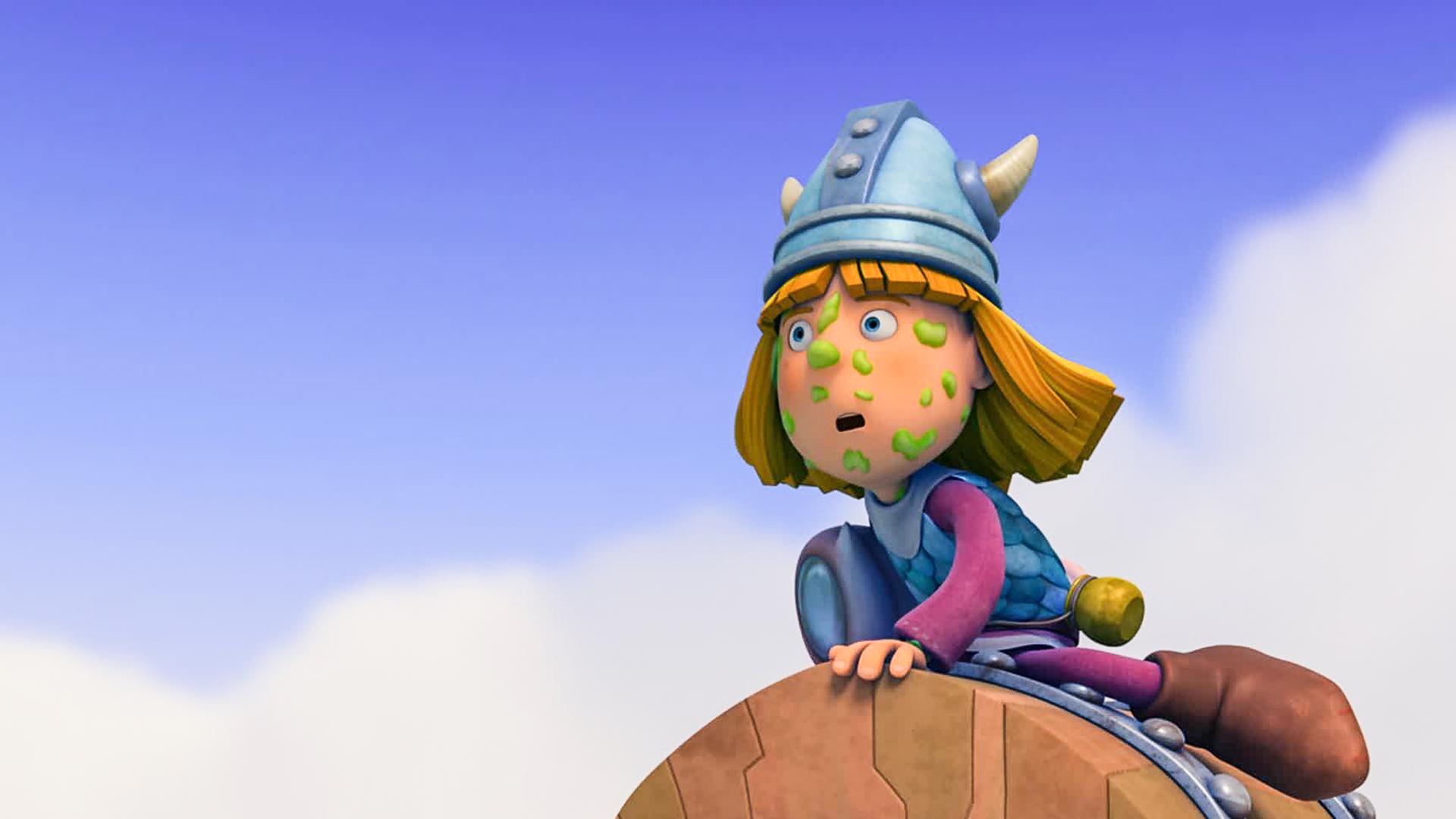 Wickie sitzt auf der Schatzkiste. Dabei hat er etwas Grünes im Gesicht kleben und schaut gespannt in die Ferne. 