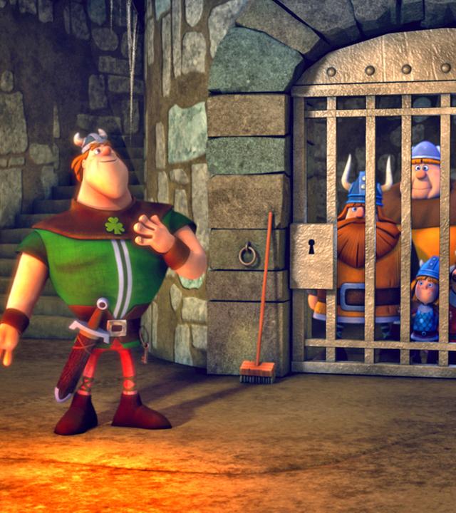 Die Wikinger sind hinter Gittern gefangen. Vor dem Gefängnis steht ein Ire und wärmt sich am Feuer.