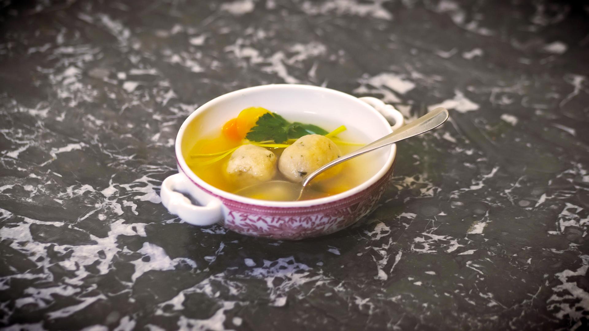 Eine Suppenschüssel mit Matzeknödlsuppe und einem Löffel.