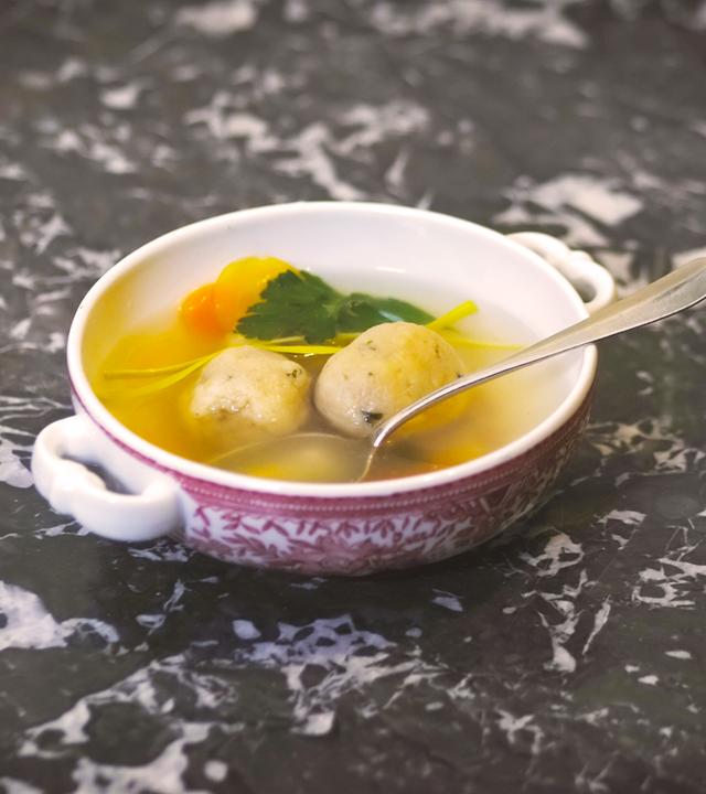 Eine Suppenschüssel mit Matzeknödlsuppe und einem Löffel.