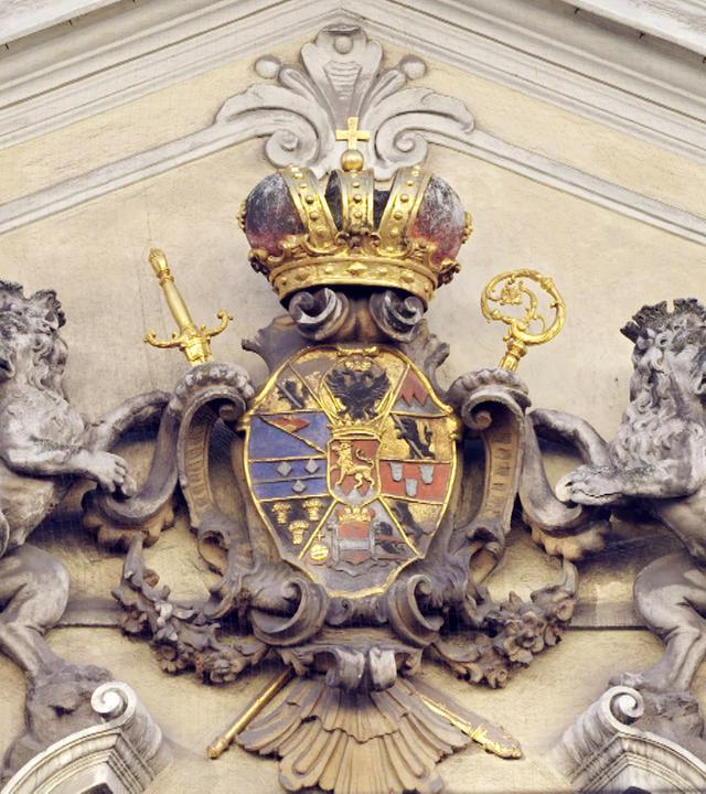 Steinlöwen halten das Wappen mit goldener Krone