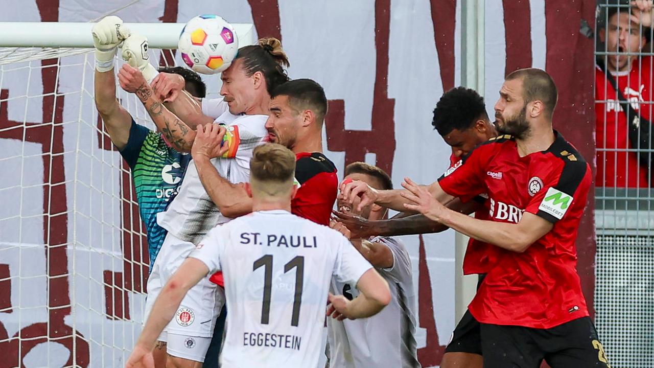 Torhueter Nikola Vasilj (St. Pauli), Jackson Irvine (St. Pauli), Johannes Eggestein (St. Pauli) und Sascha Mockenhaupt (Wiesbaden) kämpfen um den Ball am 19.05.24.
