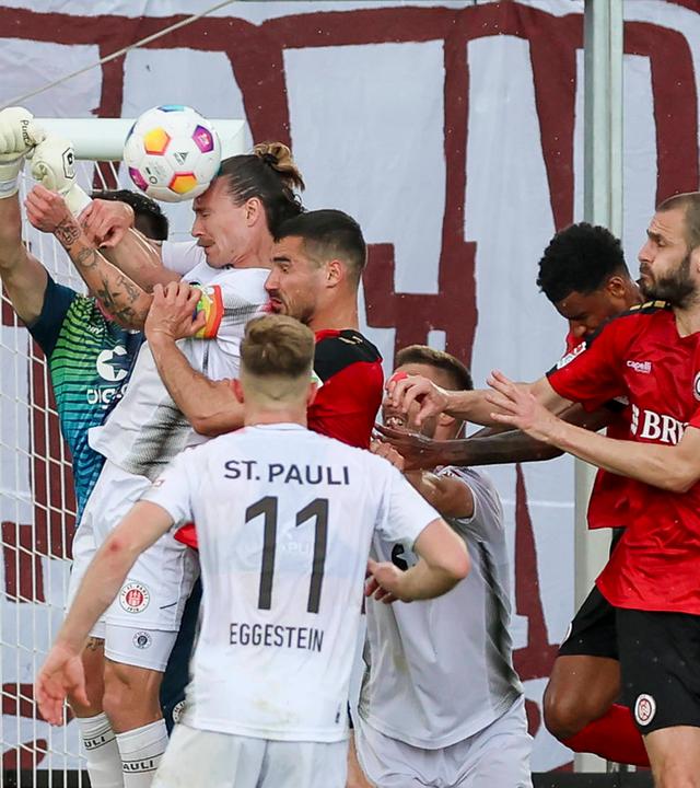 Torhueter Nikola Vasilj (St. Pauli), Jackson Irvine (St. Pauli), Johannes Eggestein (St. Pauli) und Sascha Mockenhaupt (Wiesbaden) kämpfen um den Ball am 19.05.24.