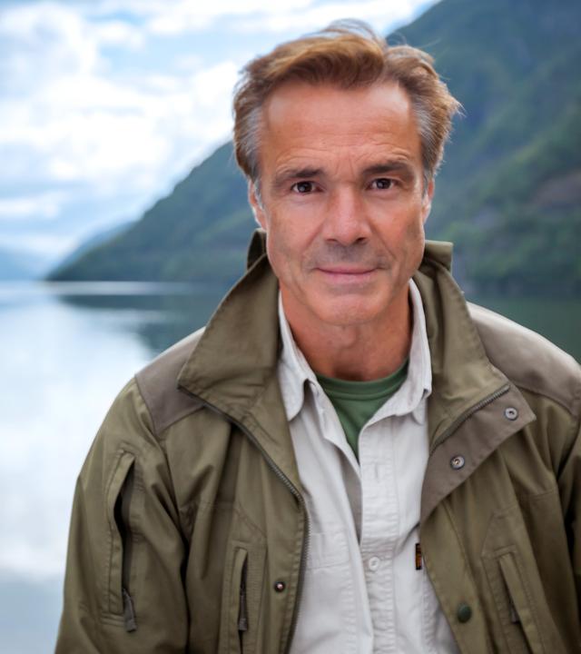 Großaufnahme von Hannes Jaenicke vor Fjordlandschaft.