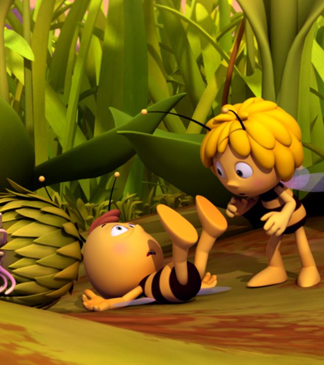 Willi liegt nach einem Sturz am Boden, die Füße in die Luft gestreckt. Maja eilt zu ihm und Kurt steht nebendran.