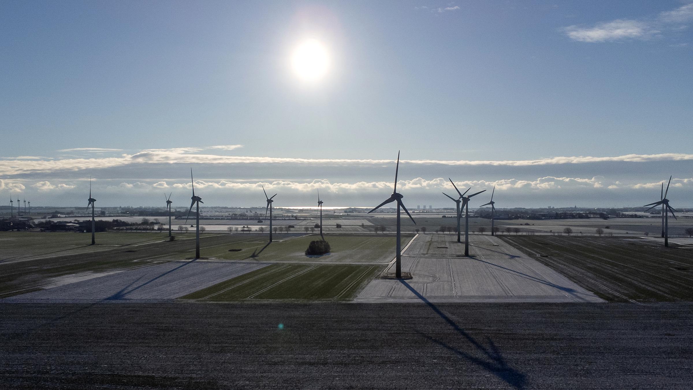 Windräder sind bei strahlendem Sonnenschein und Windstille in einem Windpark bei Puttgarden zu sehen