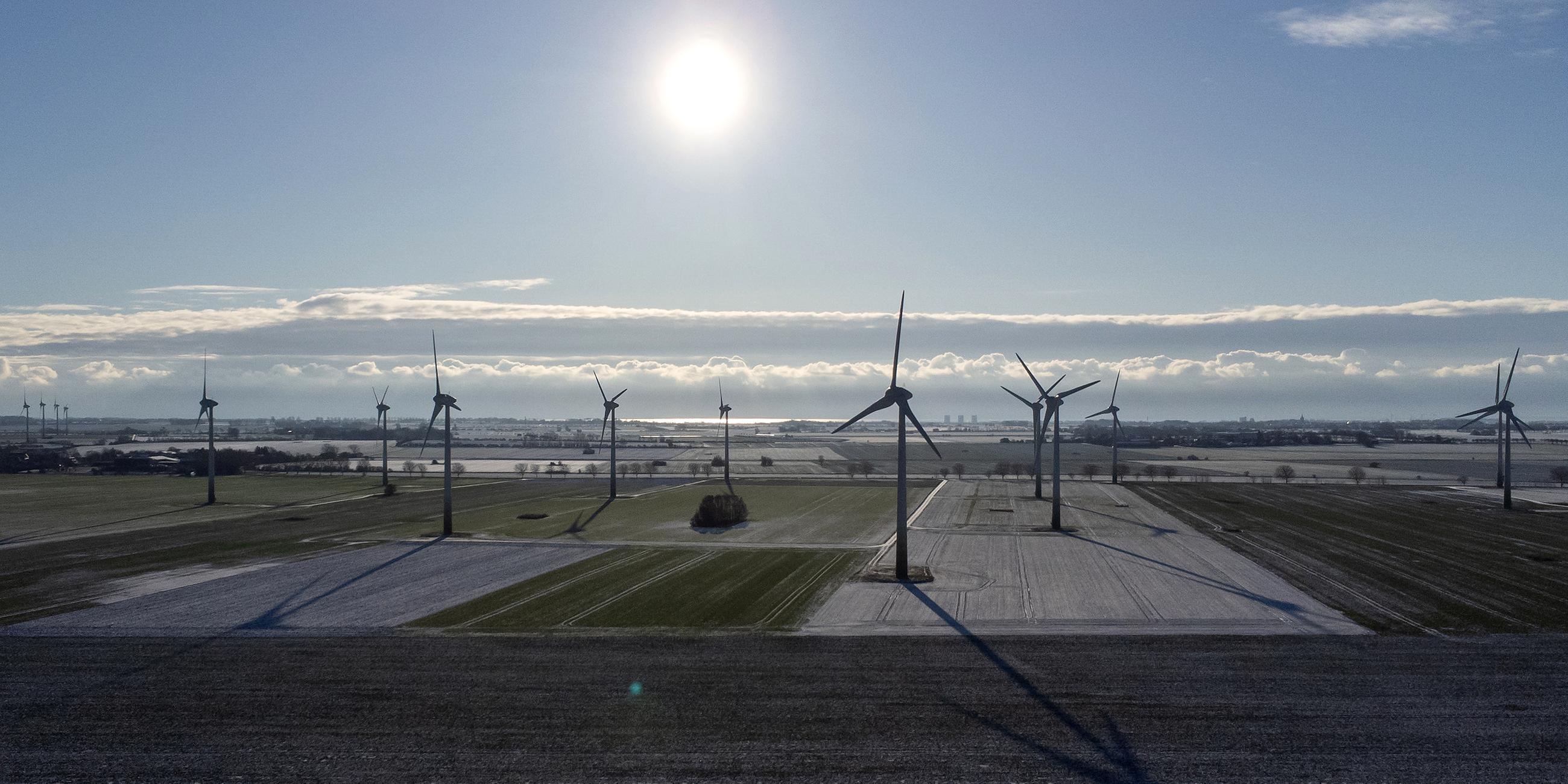 Windräder sind bei strahlendem Sonnenschein und Windstille in einem Windpark bei Puttgarden zu sehen