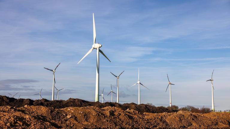 Sachsen-Anhalt, Wettin-Löbejün: Windräder stehen hinter Erdhaufen am Rande eines Baufelds