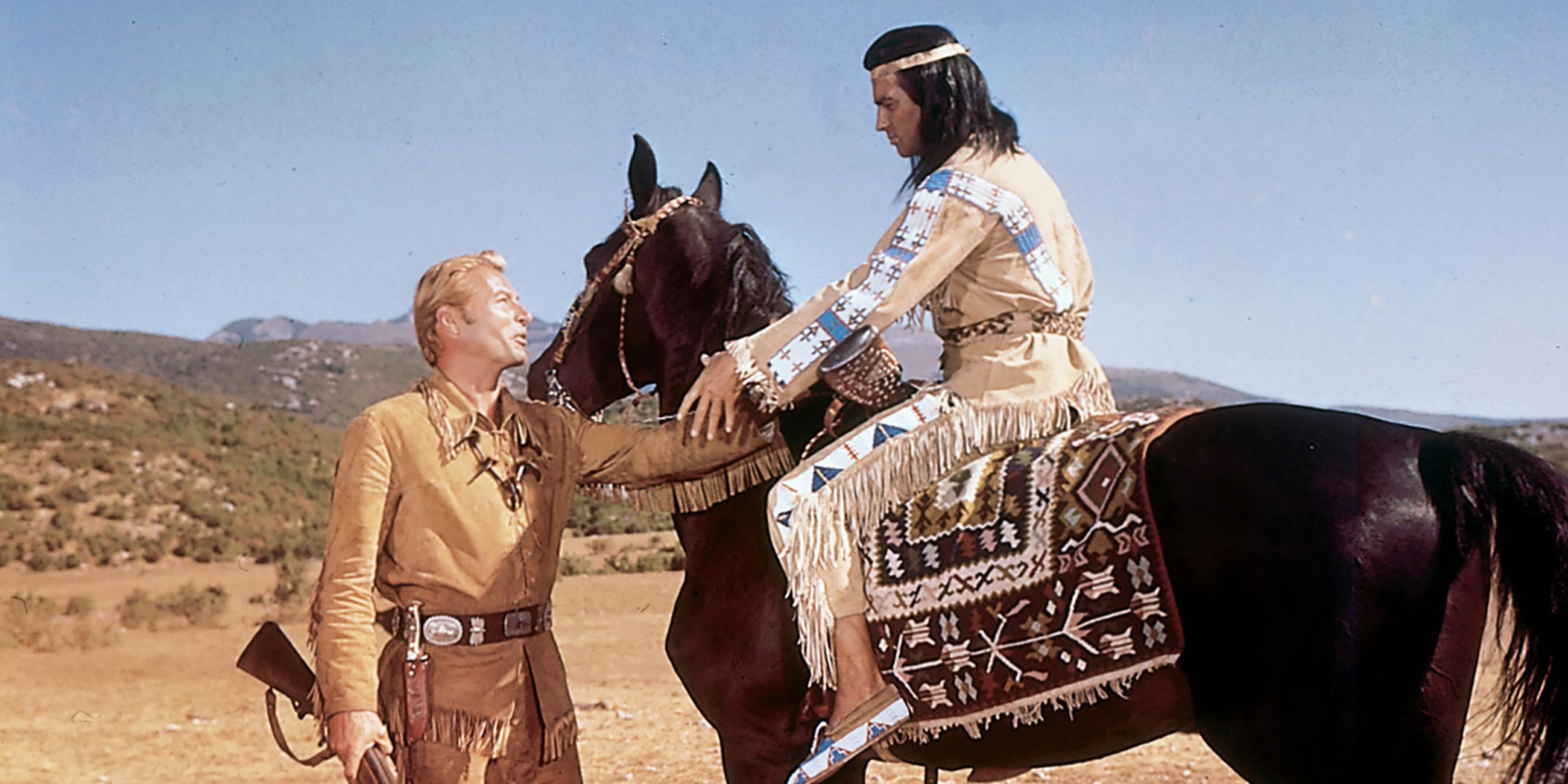 Old Shatterhand (Lex Barker) steht vor Winnetou (Pierre Brice), der auf seinem Pferd sitzt. Die beiden reichen sich die Hand.