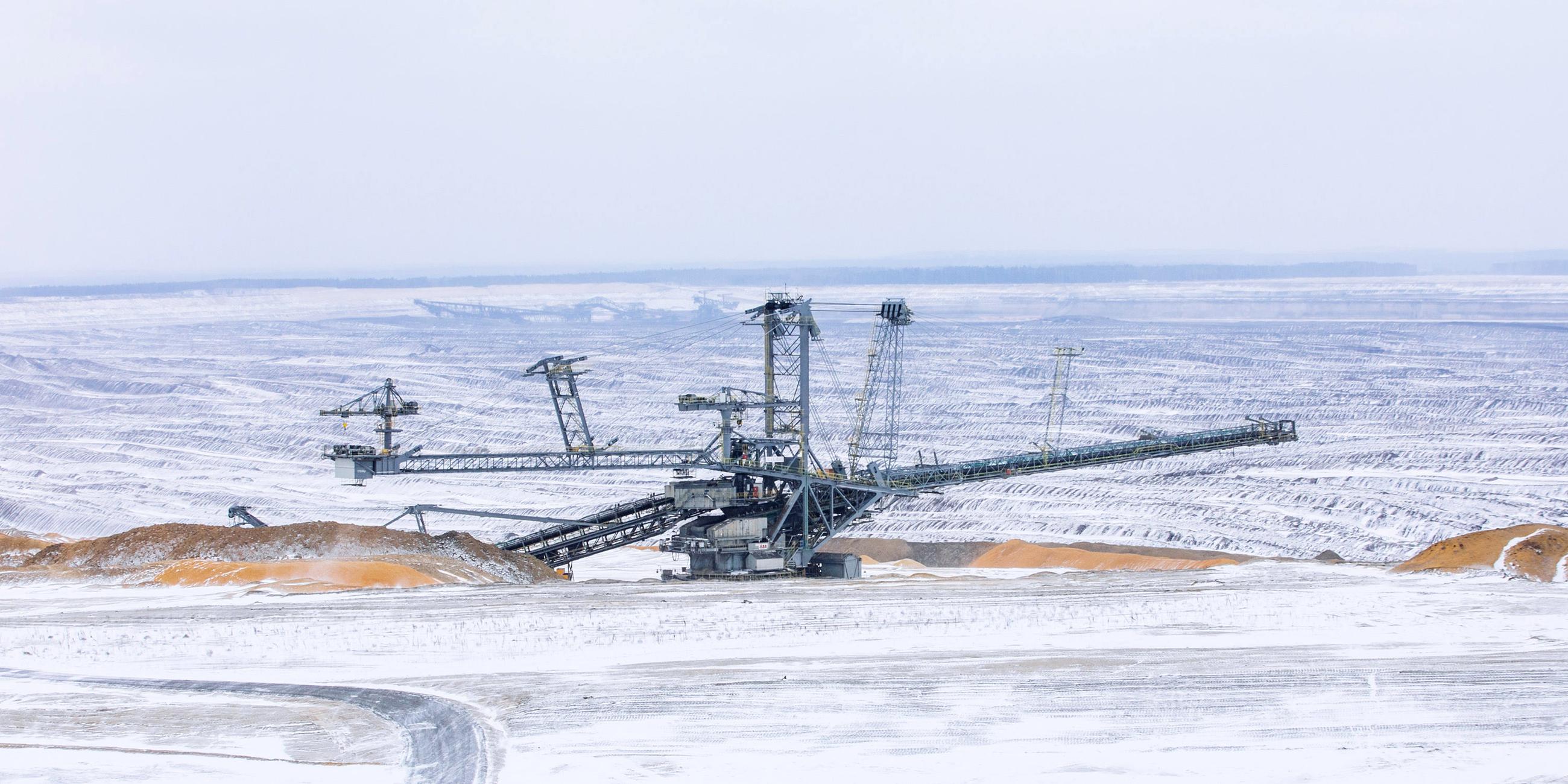 Ein Absetzer steht in der schneebedeckten Landschaft vom Tagebau Nochten