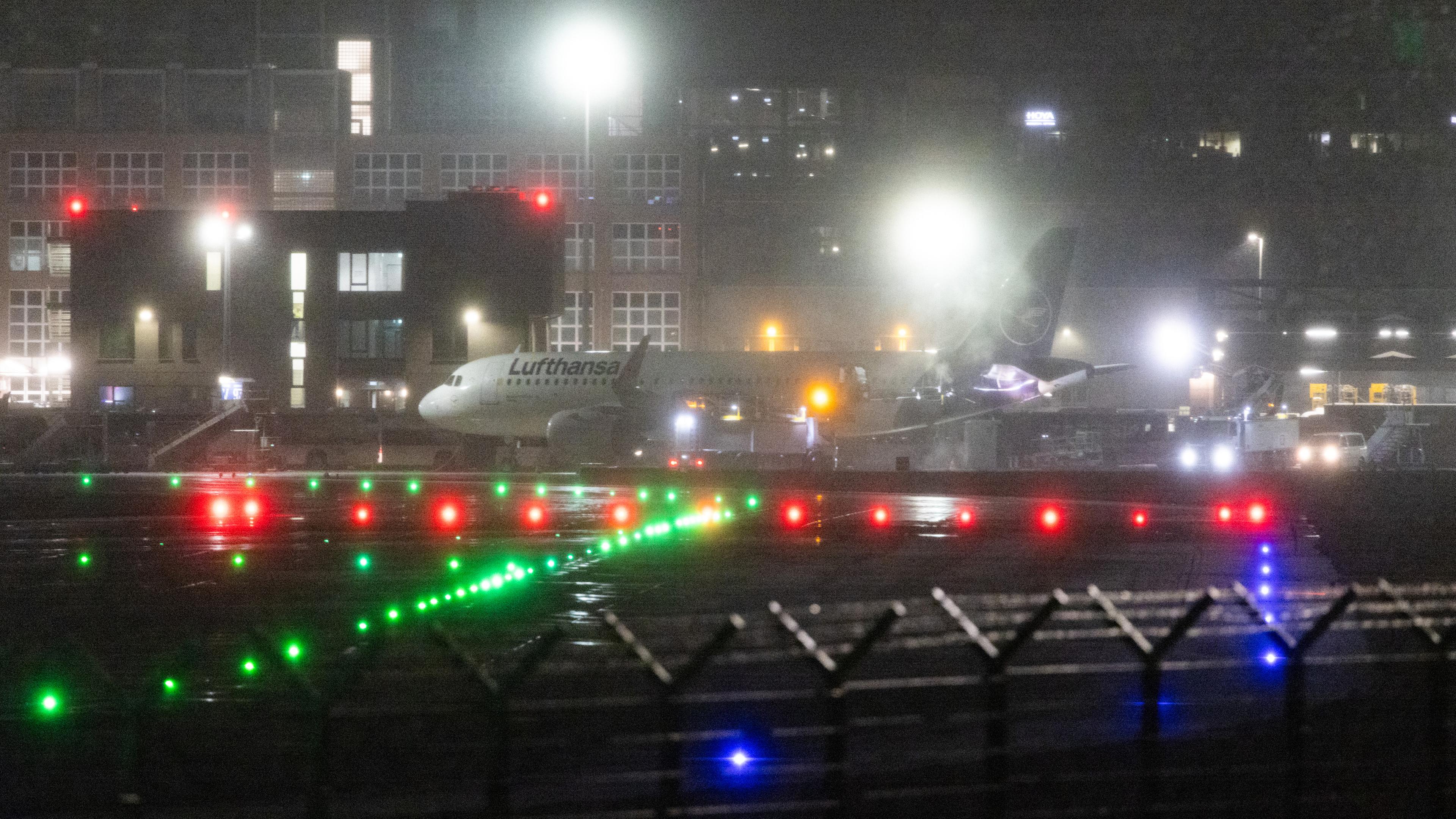  Ein Flugzeug der Lufthansa steht bei Dunkelheit und Schneefall auf dem Flughafen. (18.01.2024)