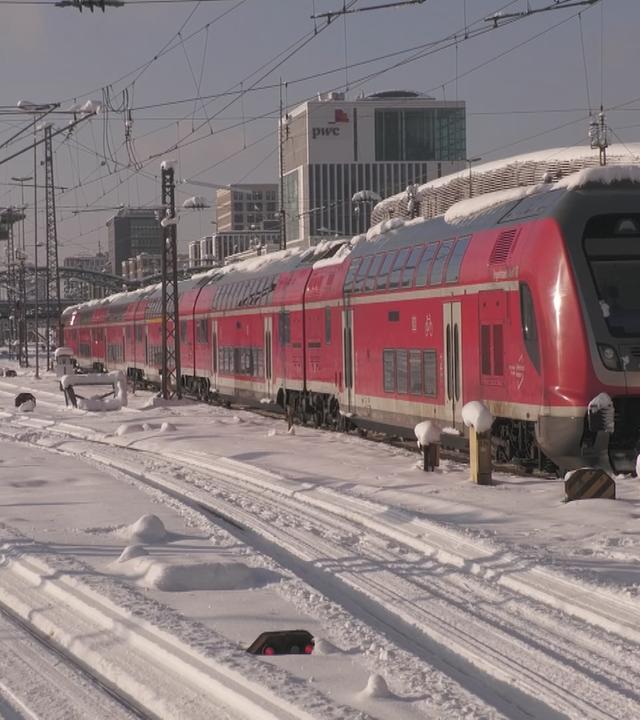 Eine Bahn steht im verschneiten Bahnhof