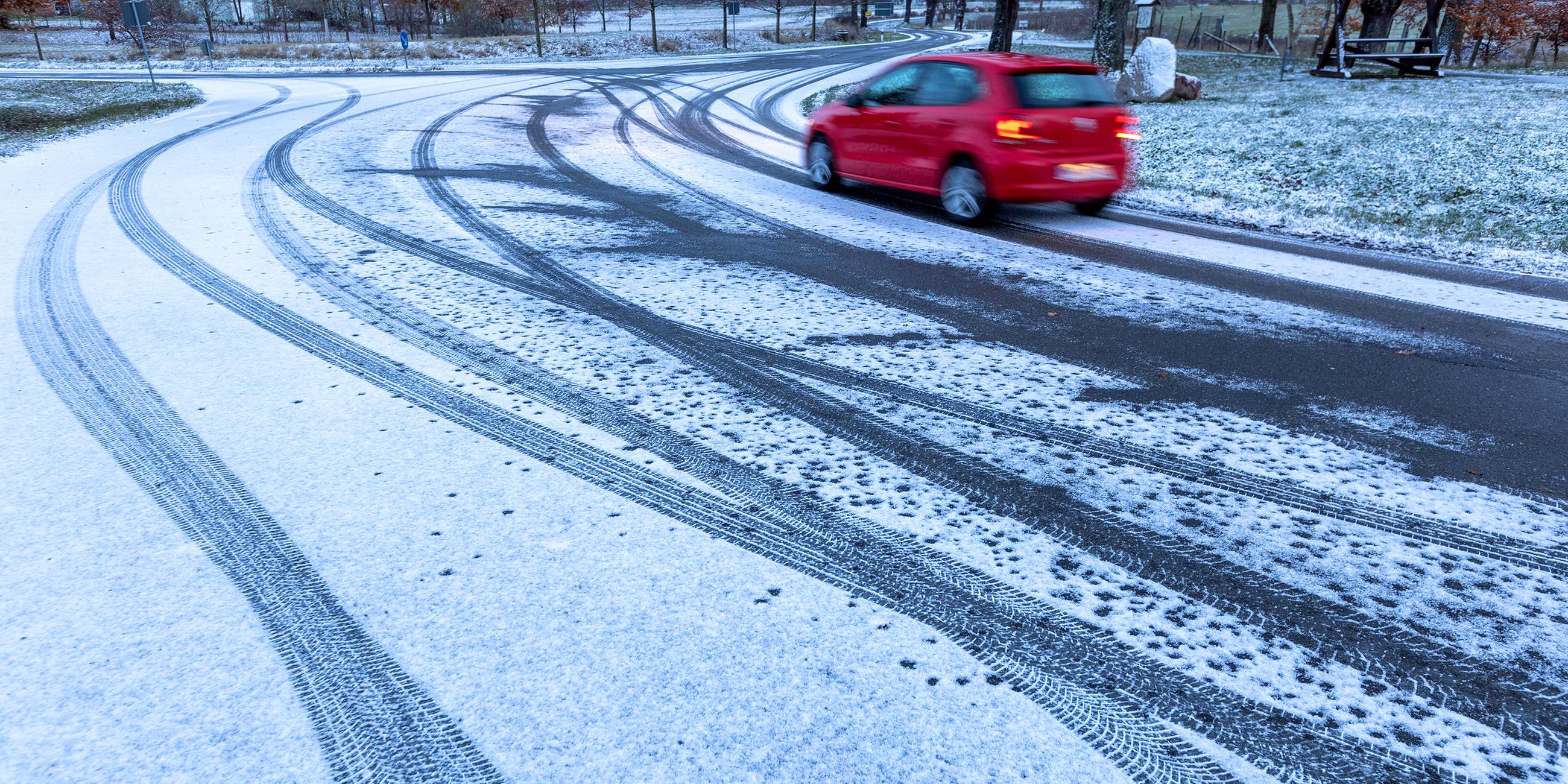  Ein Auto fährt nach leichtem Schneefall über eine Straßenkreuzung