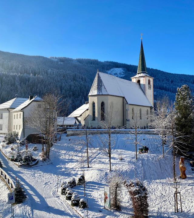 Eine Kirche und Häuser verschneit vor blauem Himmel