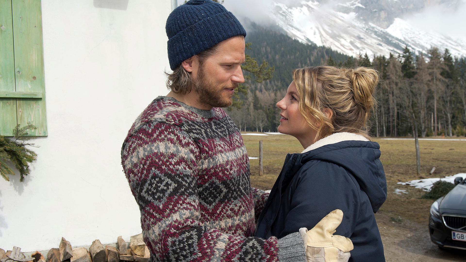 Markus (Sebastian Ströbel) und Katharina (Luise Bähr) stehen sich Arm in Arm draußen auf dem Hof gegenüber. Sie blicken sich lächelnd an.