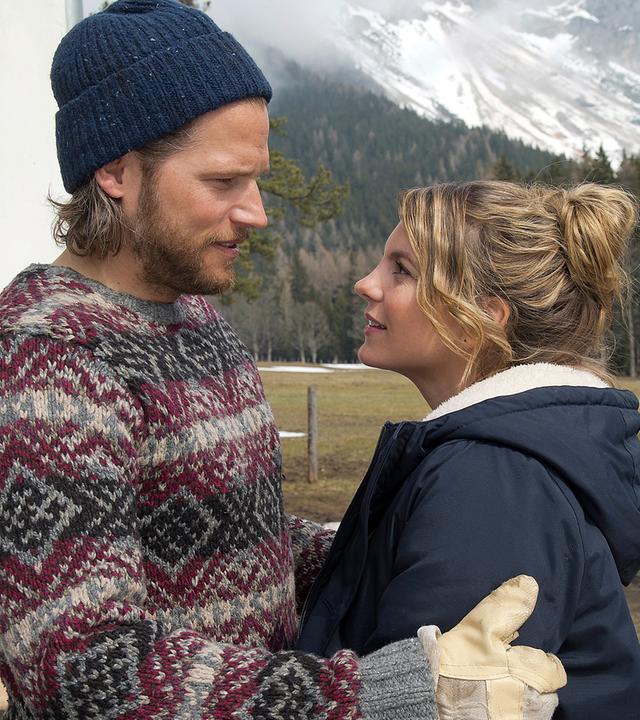 Markus (Sebastian Ströbel) und Katharina (Luise Bähr) stehen sich Arm in Arm draußen auf dem Hof gegenüber. Sie blicken sich lächelnd an.