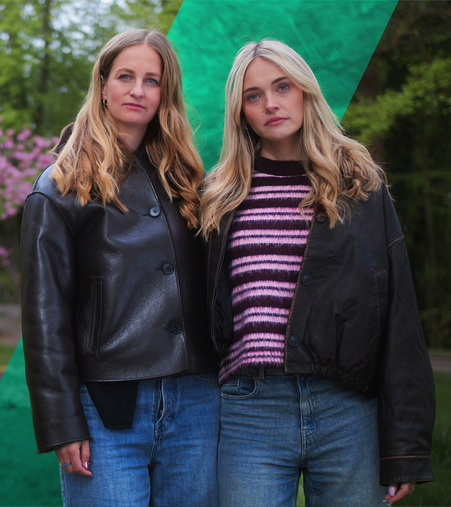 Malou und Jana stehen nebeneinander. Im Hintergrund ist eine Parkanlage zu sehen, mittig ein blühender Baum.