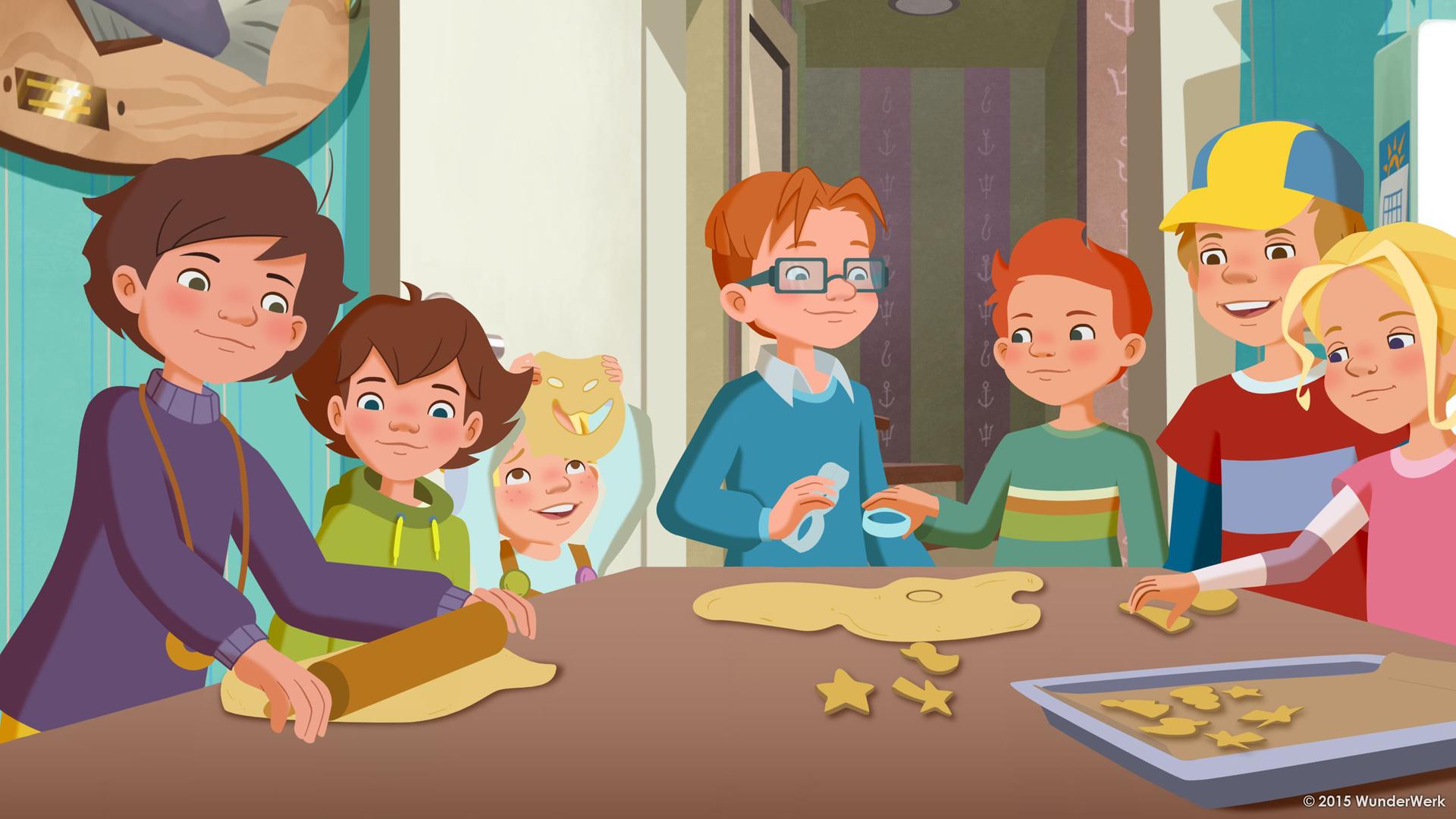 Alle Möwenweg-Kinder backen zusammen Kekse. Sie stehen alle um einen großen Tisch herum.